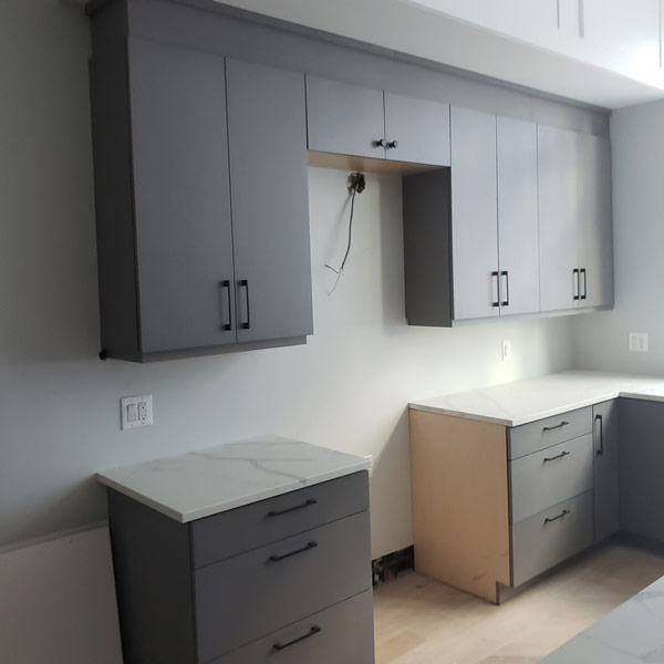 Kitchen with gray cabinets and white counter tops.