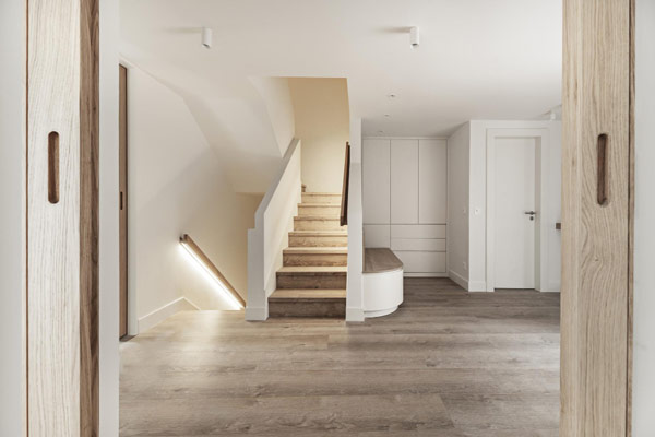 A well-lit hallway with polished wooden floors and pristine white walls.