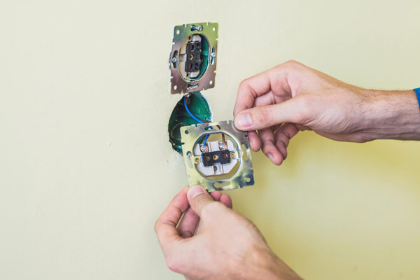 A person skillfully repairing a light switch with focused concentration and precision.